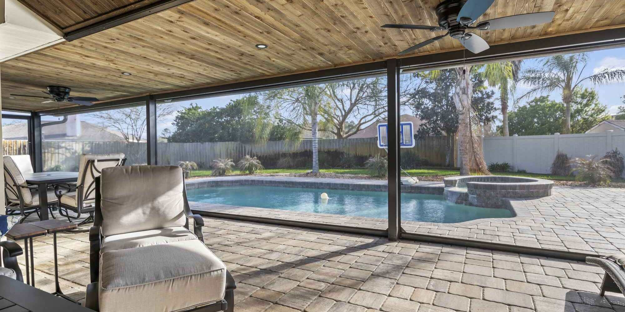 A covered patio with a roof and motorized screens in Jacksonville, FL by Impact Enclosures