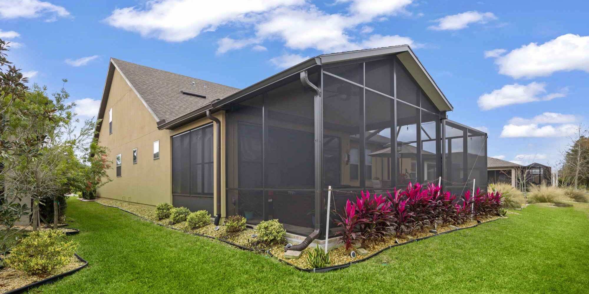 Exterior view of a large black screen room with a roof and ceiling fan in Jacksonville, FL by Impact Enclosures