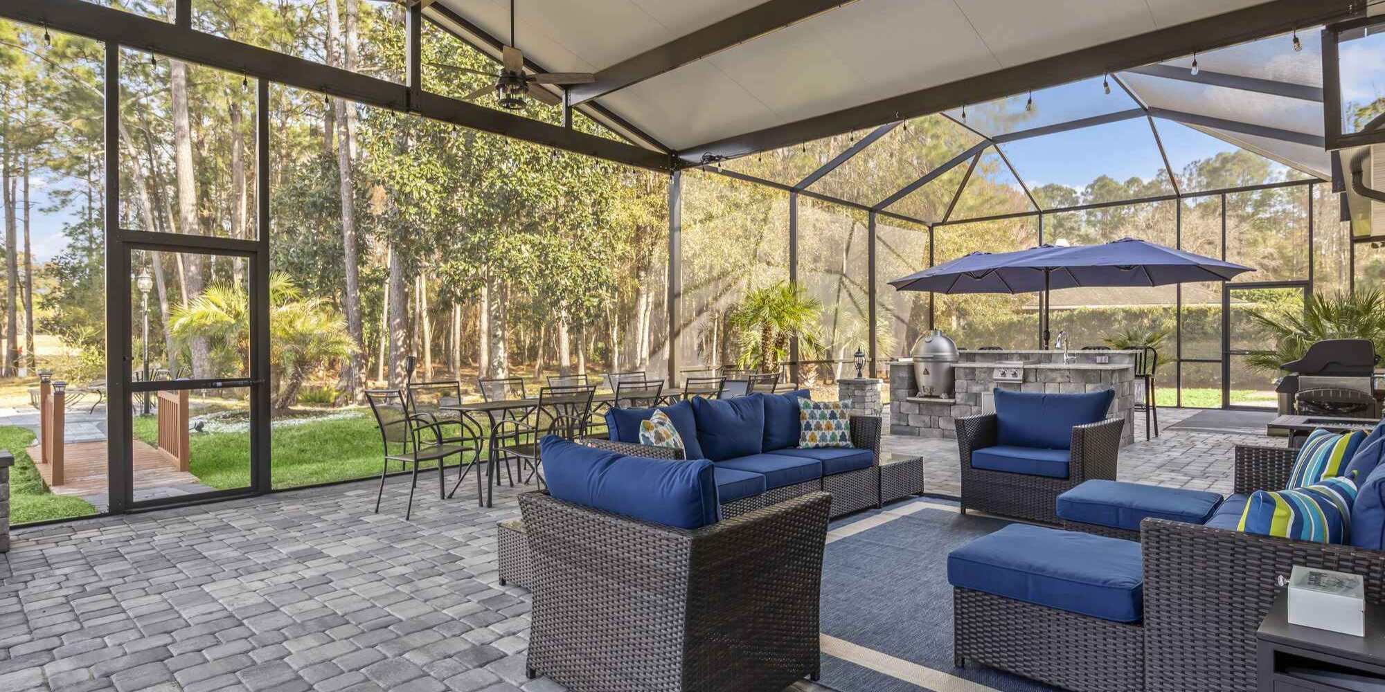 Interior view of a Jacksonville screen room around a patio with dining and lounging spaces by Impact Enclosures