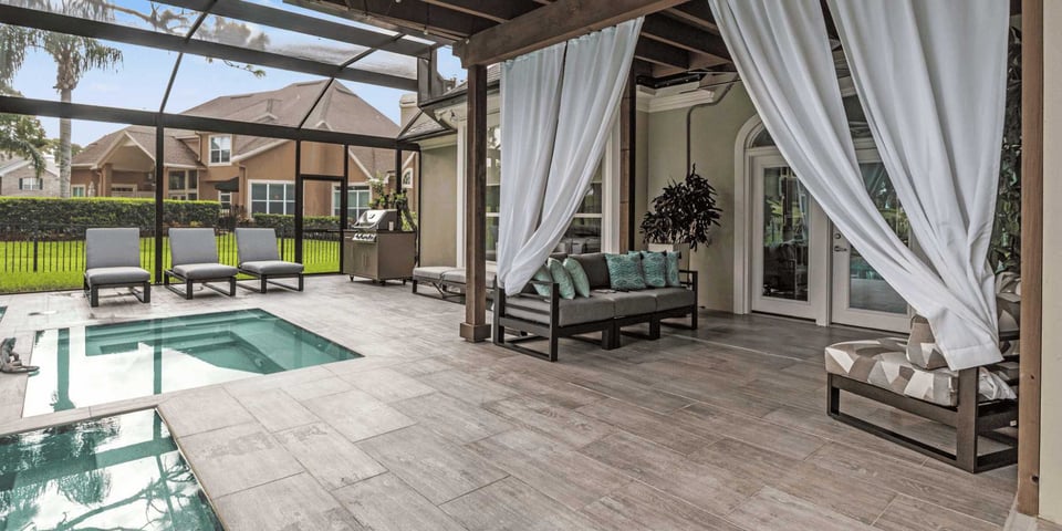 Image of a backdoor enclosure with patio pavers, pool, hot tub, and screen by Impact Enclosures