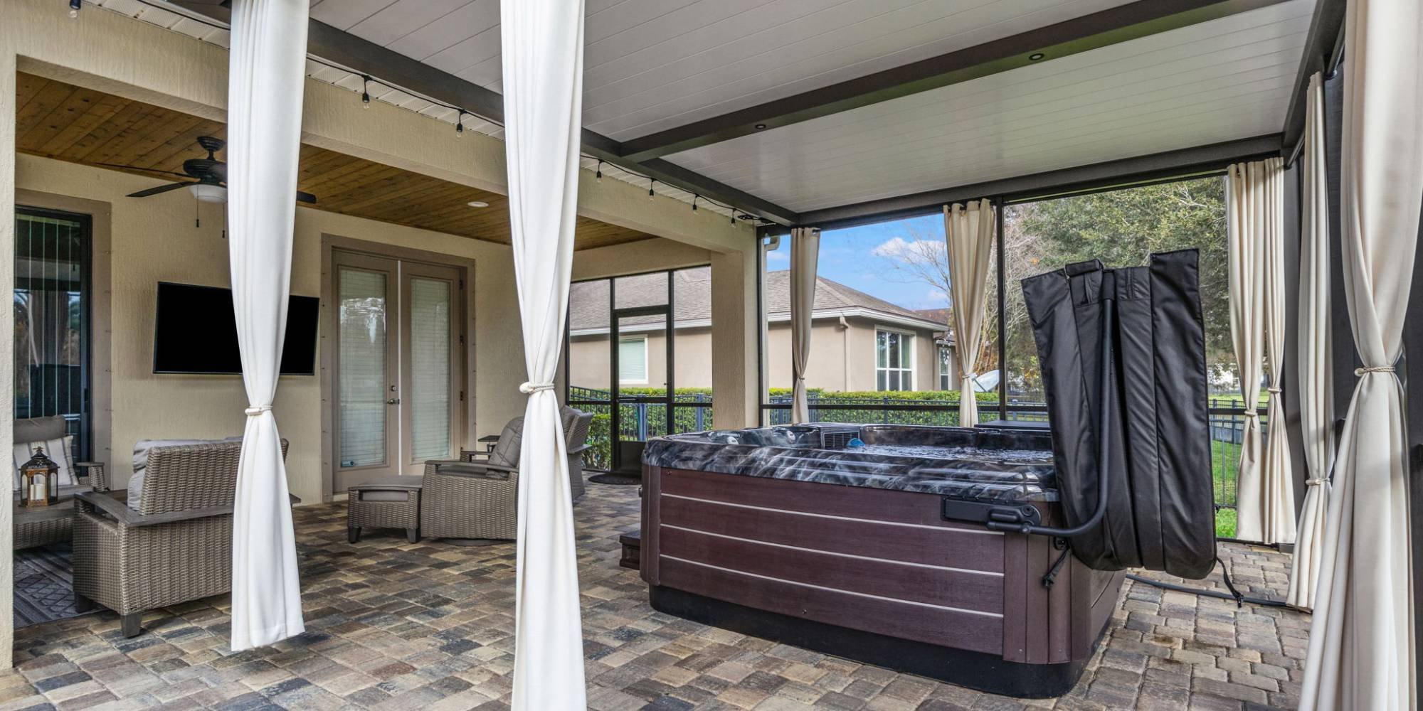 Screen room with seating and a hot tub by Impact Enclosures in Jacksonville, FL