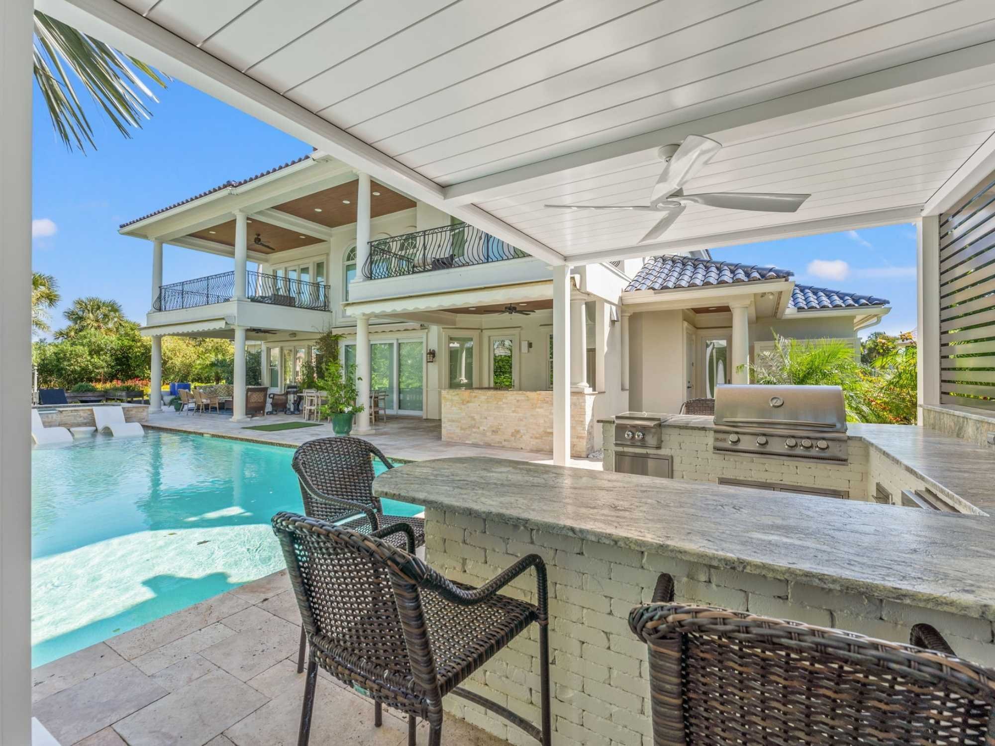 Image of an outdoor kitchen with pergola and swimming pool by Impact Enclosures in Ponte Vedra Beach, FL