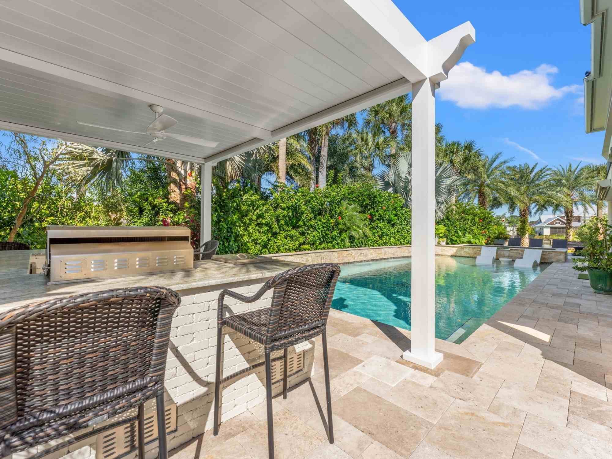 Image of the outdoor kitchen, pergola, pool, with stone patio in Ponte Vedra Beach, FL by Impact Enclosures