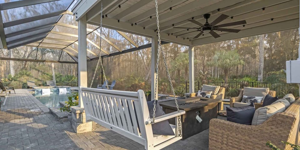 Covered patio and screened pool enclosure by Impact Enclosures in Jacksonville, FL with outdoor seating and swing