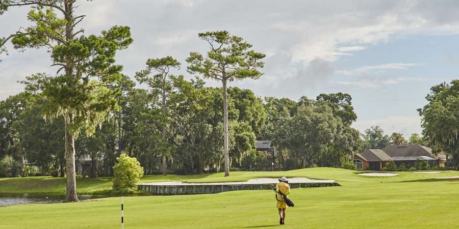 Golfer walking toward the grass at Queens Harbour Golf Course - Top Golf Communities in the Jacksonville