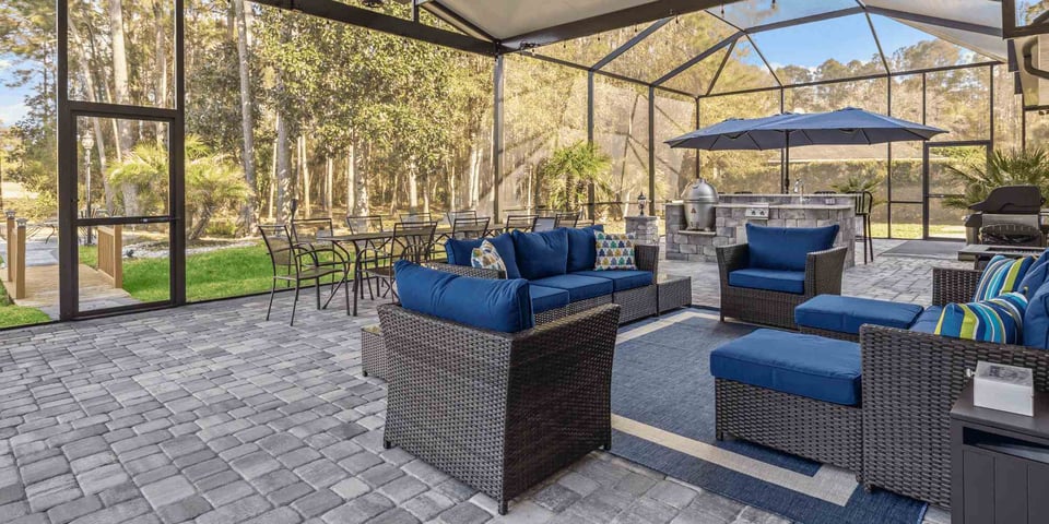 Image of a screened in patio with seating area and outdoor kitchen by Impact Enclosures in Jacksonville, FL