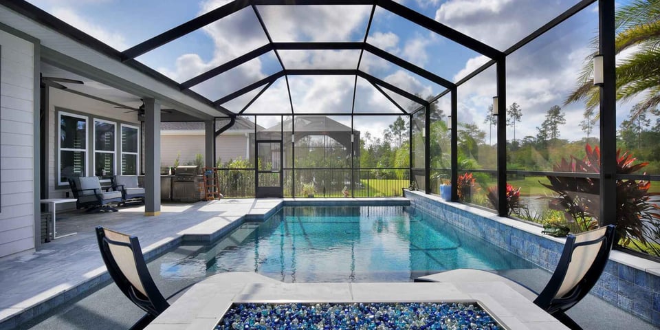 Modern screened pool enclosure by Impact Enclosures in Jacksonville, FL with outdoor seating and grill area